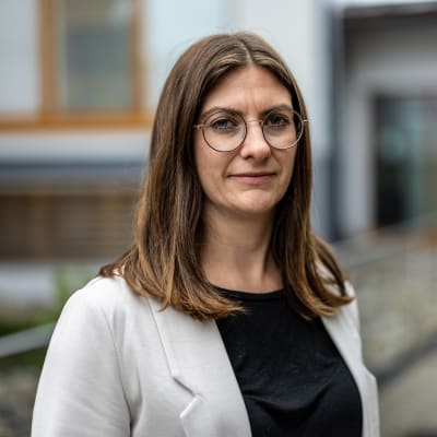 Porträttfoto av kvinna framför skolbyggnad