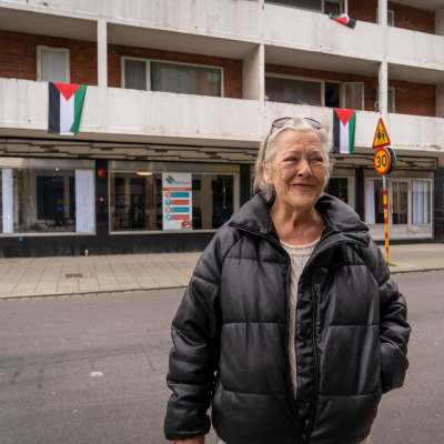 Ing-Marie står framför balkonger där det hänger Palestinaflaggor.