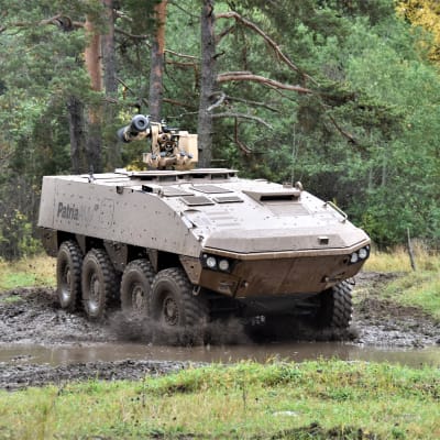Patria AMVXP 8x8 panssaroitu pyöräajoneuvo syksyisessä, kuraisessa maastossa. Taustalla metsää.