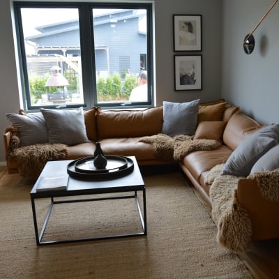 ett vardagsrum i bruna färger med en brun lädersoffa.
