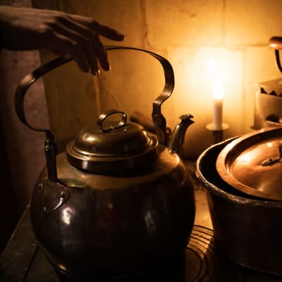 en kastrull och en kaffepanna som står på en gammal gjutjärnsspis i julbelysning
