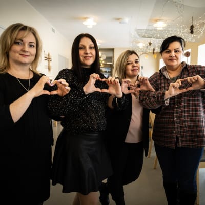 En grupp av kvinnor håller upp händerna formade till hjärtan