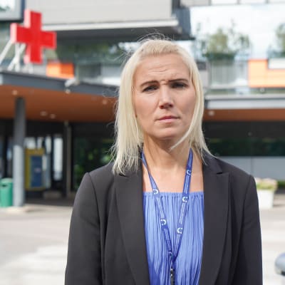 Blond kvinna i svart kavaj och blå blus står framför akuten i Vasa.