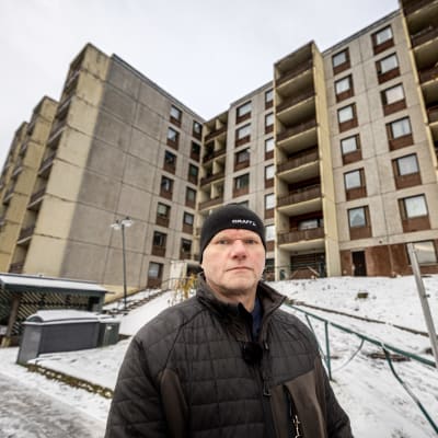 Pensionerade Åbopolisen Vesa Jauhiainen står framför höghus i Kråkkärrets förort.