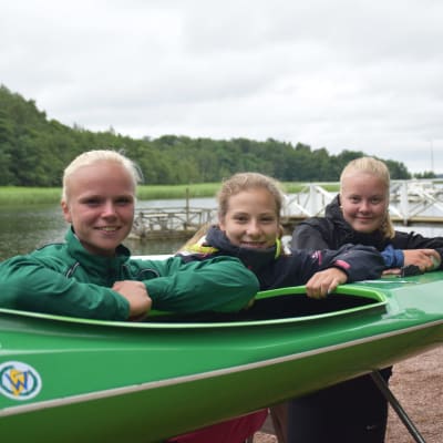 Emma Malmsten, Elvira Johansson och Jenni Sandberg lutar mot en kanot.