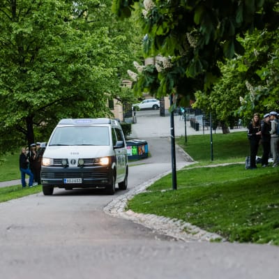 Poliisiauto ajaa puistossa jossa ylioppilaat juhlivat.