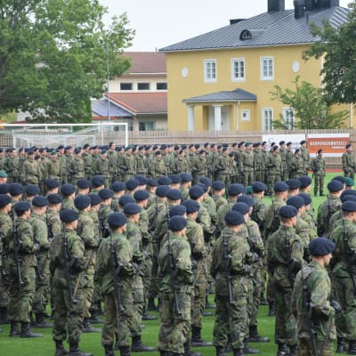 Militärparad med rekryter ute på en gräsplan. 
