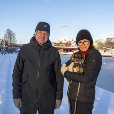 Christer och Tarja Hublin vid ett fruset Borgå å med hunden Nappi i famnen.