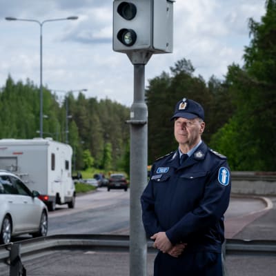 Polisen Heikki Ihalainen står bredvid en fortkörningskamera.