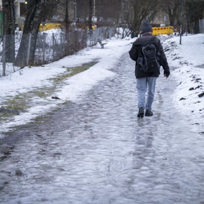Mies kävelemässä jäätyneellä kevyenliikenteen väylällä Pohjois-Haagassa.