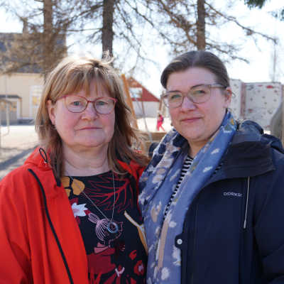 Två kvinnor står på en skolgård.