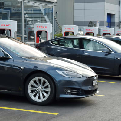 Tre Teslabilar parkerade vid laddningsstationer.