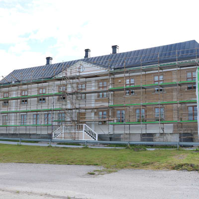 En husfasad som renoveras. Längs med hela fasaden har byggställningar lagts upp.