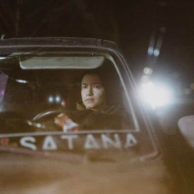 Nainen istuu autossa.