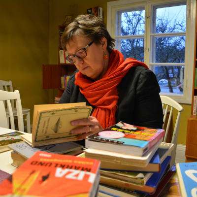 Kvinna sitter och bläddrar i en bok.