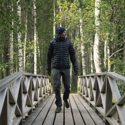 Tiilikkajärven kansallispuiston suunnittelija Marko Haapalehto kävelee sillalla metsämaisemassa.
