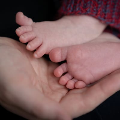 Vauvan jalat äidin kämmenellä.