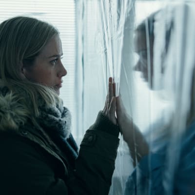Nina Kautsalo (Iina Kuustonen) seisoo muovin toisella puolella ja hänen siskonsa (Pihla Viitala) toisella puolella kädet muovin läpi koskettaen.