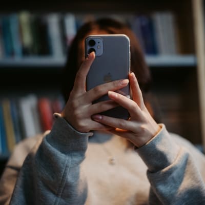 En skolelev håller upp en mobiltelefon framför ansiktet. 