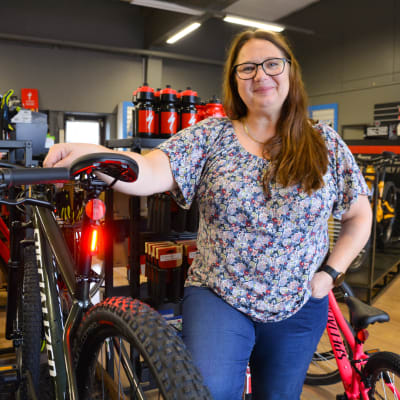 En kvinna i en cykelaffär, bredvid en cykel med baklykta.