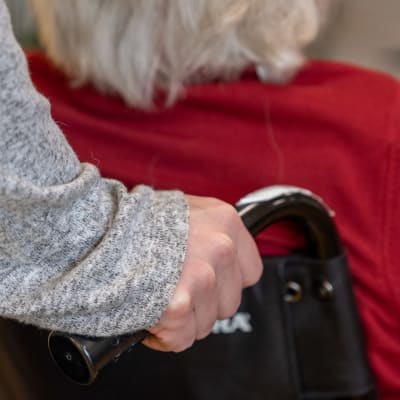 Äldre person skuffas i rullstol