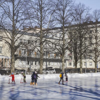 Elever från Zacharias Topeliusskolan skrinnar på isplanen i Författarparken i Helsingfors.