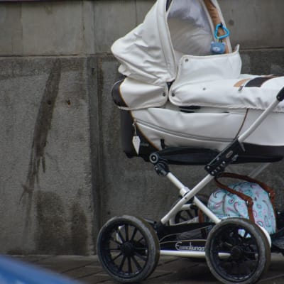 En vit barnvagn med betong i bakgrunden. 
