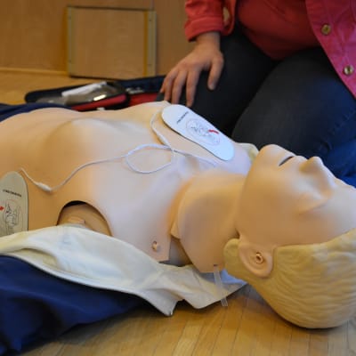 Kvinna visar hur en defibrillator fungerar.