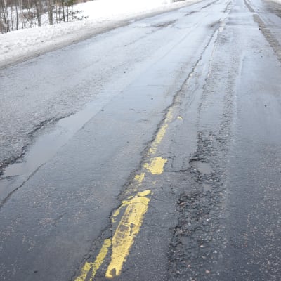 En asfalterad väg med skador i beläggningen.