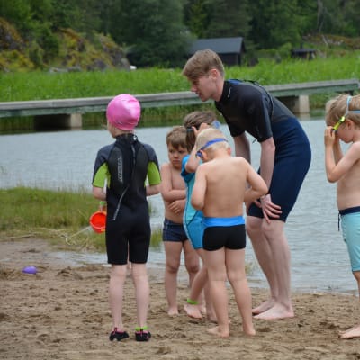 Simskolelärare Anton Ristimäki uppmuntrar barnen att våga sig i vattnet.