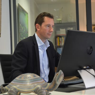 Jan D. Oker-Blom tittar på en skärm vid sitt arbetsbord.