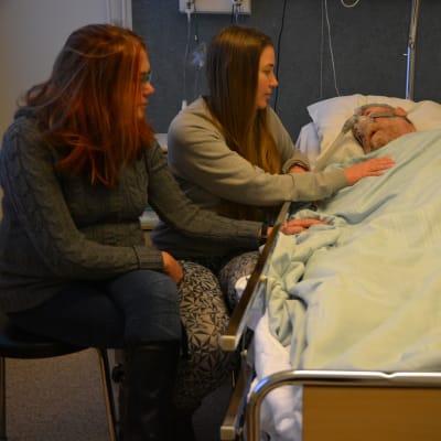 Carola Backholm (till vänster) och Tina Norrgrann hälsar på sin pappa Frank på Vasa centralsjukhus.