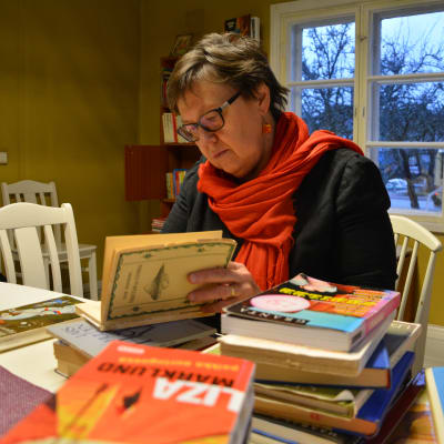 Kvinna sitter och bläddrar i en bok.