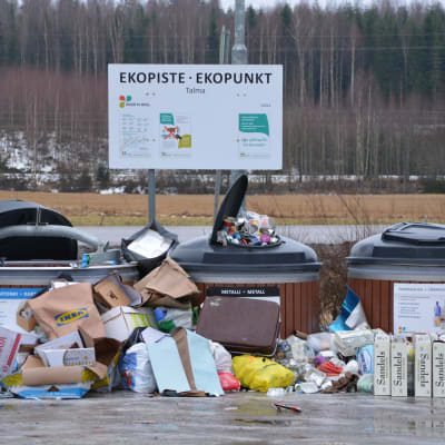 Stora avfallsbehållare för papper, kartong och metall med en massa skräp utanför.