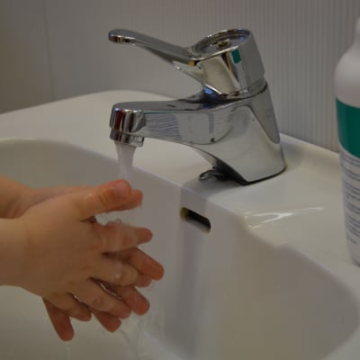 Ett barn tvättar sina händer i ett tvättställ. 