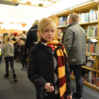 Bild på Aron Eklund, som står med halsduk, kåpa och trollstav på Harry Potter- evenemang.