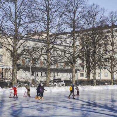 Elever från Zacharias Topeliusskolan skrinnar på isplanen i Författarparken i Helsingfors.