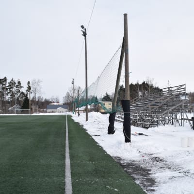 Karis konstgräsplan är grön eftersom den är uppvärmd i mars, men med snöhögar kring planen.