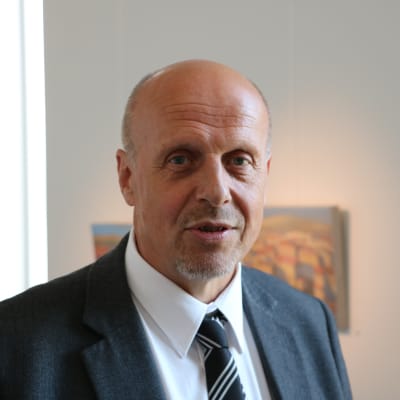 Göran Honga står i mörk kavaj i ett galleri i Närpes.