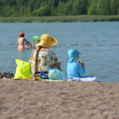En kvinna och ett barn som sitter på en strand. 