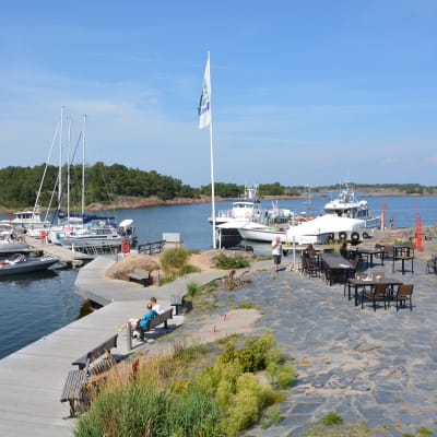 Segelbåtar i Örö gästhamn, och kafégäster i hamnen.