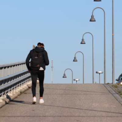 En ungdom går ensam över en tom bro.