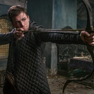 Taron Egerton poserar med pil och båge.