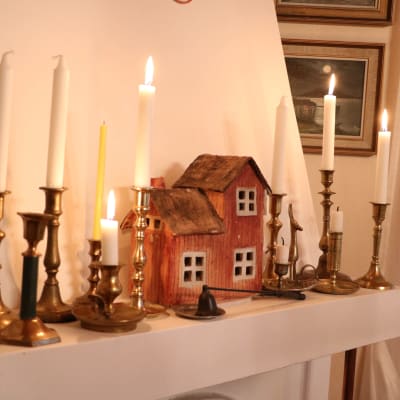 Ett miniatyrhus samt flera ljus står på spiselkransen.