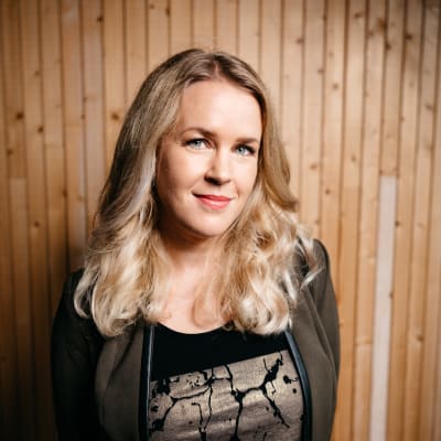Hannah Norrena står inomhus mot en trävägg
