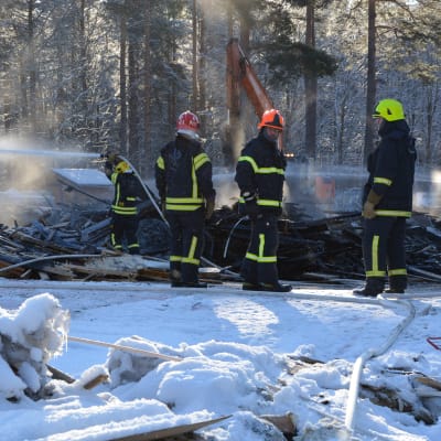 Brandmän håller på med eftersläckning vid en brand.