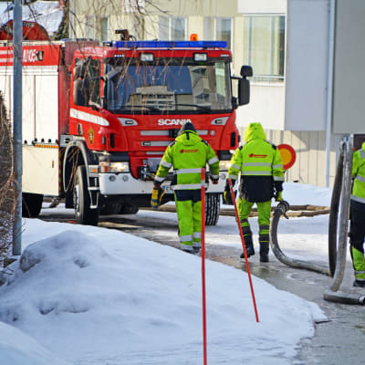 Män bär på rör och går mot brandbil