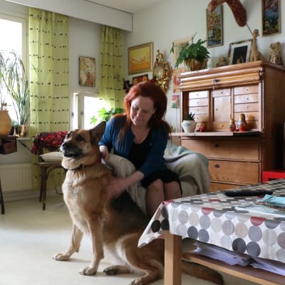 Lena Bengtson sitter i sitt vardagsrum med schäferhunden Alice bredvid sig.