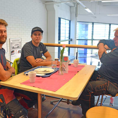 Tre män som sitter vid ett bord på en lunchrestaurang.