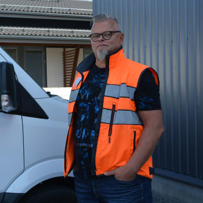 Man i arbetsväst bredvid paketbil.